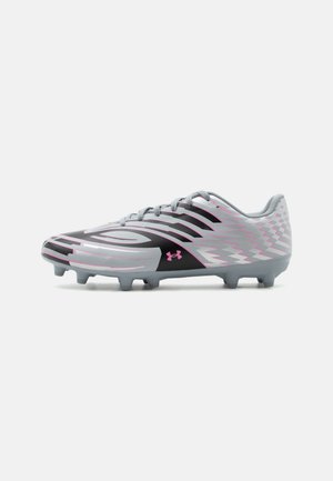 Chaussure de football grise et noire avec motifs en zigzag roses, lacets et crampons sous la semelle, vue de profil sur fond blanc.