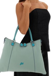 Borsa tote in pelle azzurro chiaro con due manici e dettagli turchesi. Presenta ferrature argentate e logo impresso sulla parte anteriore.