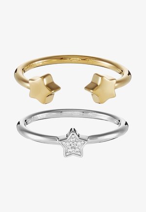 Deux bagues sur le thème des étoiles, une bague ouverte en or avec des étoiles pleines aux extrémités, une bague fermée en argent avec une étoile ornée de petits cristaux.
