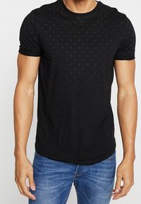 Camiseta negra de manga corta con un sutil patrón de puntos, fabricada en una tela suave, con un cuello redondo y un diseño ajustado.