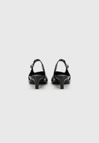 Mustast nahast konksu-kontsad avatud kanna ja reguleeritava ankle strap'iga. Sile tekstuur ja minimalistlik disain.
