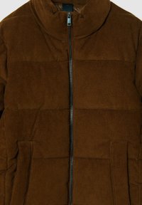 Giacca puffer in corduroy marrone con colletto alto, zip frontale e due tasche laterali. Tessuto testurizzato con motivo a coste.