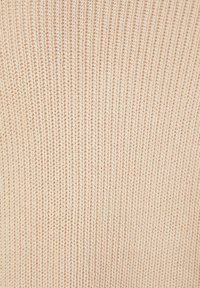 Tissu tricoté beige clair avec une texture côtelée, présentant des lignes verticales uniformément espacées sur l'ensemble du matériau.