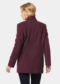 Burgunderfarbener Wollmantel mit strukturiertem Design, elongated Form und Kragen. Verfügt über vordere Nähte und Seitentaschen.