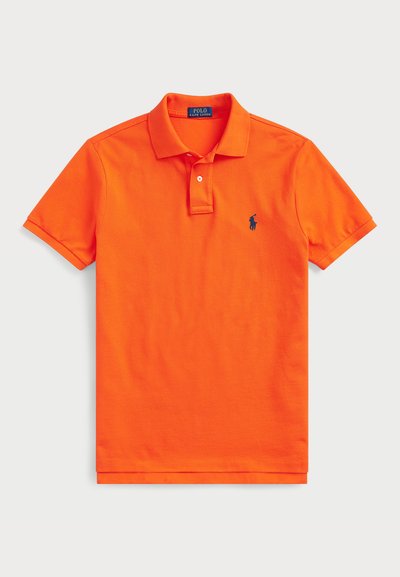 Klassikaline oranž puuvillane polo särk, millel on klassikaline krae, kahe nupuga sulgemine ja väike must logo vasakus rinnas.