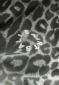 Svart tyg med ett grått leopardmönster; vit text som lyder "SAINT LONDON" framträdande i mitten.