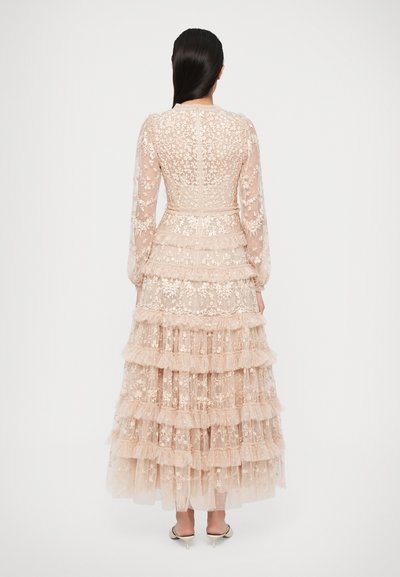 Ilga, sluoksniuota suknelė iš permatomo smėlio spalvos audinio su gėlių siuvinėjimu, turinti ilgas rankoves, prigludusį liemenį ir volanų apdailą apačioje.