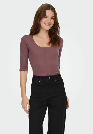 Tætsiddende, ribbet langærmet top i mauve med en rund halsudskæring, parret med høj talje sorte jeans. Enkelt tekstur, ingen synlige mønstre.