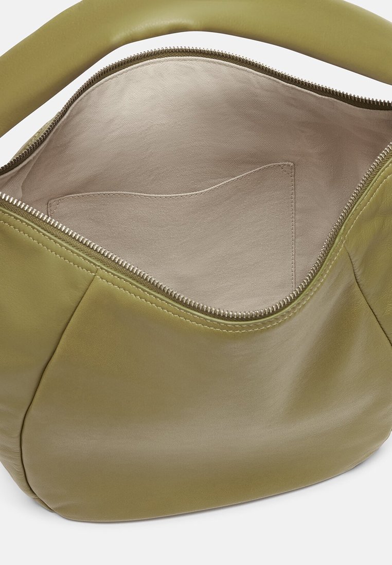 Grüner Lederhandtaschen-Innenraum mit einem beigen Stofffutter und einer einzelnen Tasche zur Organisation, mit einem Reißverschlussverschluss.