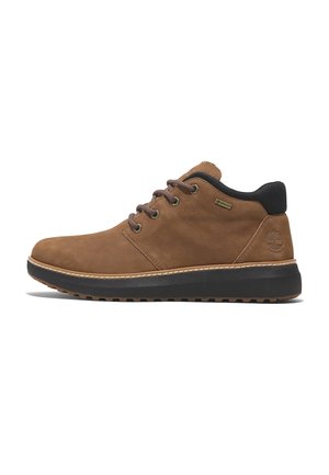 Chaussures en suede marron avec des accents noirs, design à lacets, col rembourré et semelle en caoutchouc texturée, avec des détails cousus et un logo.