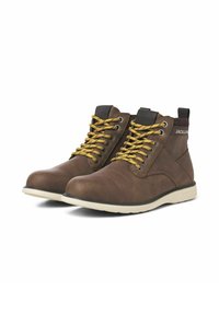 Bottines en cuir marron avec des lacets jaunes, surface texturée, semelle en caoutchouc blanche et détail du logo sur le talon.