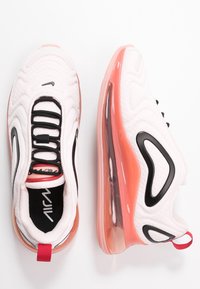 Białe buty sportowe mają teksturowaną cholewkę, czarne sznurówki i uderzającą, różową przezroczystą podeszwę. Wygięte czarne akcenty podkreślają ich design.