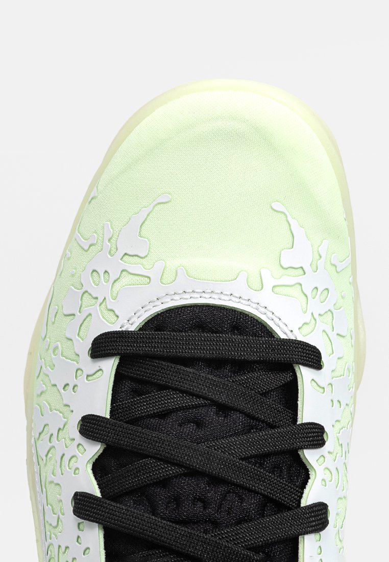 Zapatilla verde lima con diseño recortado en blanco, cordones texturizados negros y una puntera lisa; suela de goma visible.