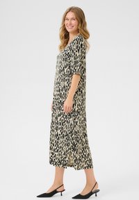Black and beige midi dress with a loose fit, featuring a V-neck, short sleeves, and a textured pattern. Paired with black slingback shoes.
