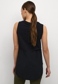 Top senza maniche nero con un orlo asimmetrico e una texture liscia, dotato di un collo arrotondato e una vestibilità morbida.