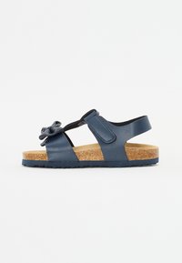 Blå sandal i syntetisk materiale med korksåle. Har en blomsterdekorasjon, justerbar reim og åpen design for pusteevne.