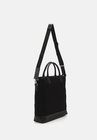 Sac fourre-tout noir en tissu avec des accents en cuir, dot é de deux poignées supérieures et d'une bandoulière réglable. Design simple et structuré.