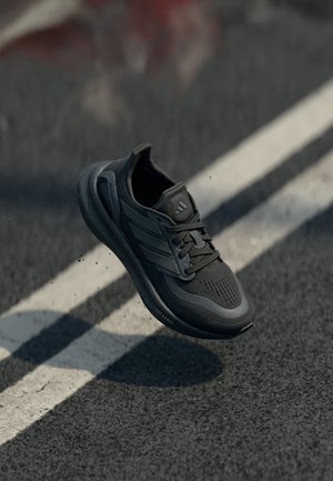 Sort sportssko med en tekstureret overdel, der har tre striber på siden, en rund tå og en polstret sål. Light Boost-teknologi.