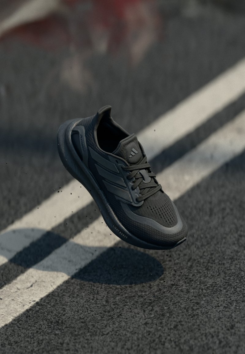Black athletic shoe with a textured upper, featuring three stripes on the side, a rounded toe, and a cushioned sole. Light Boost technology.