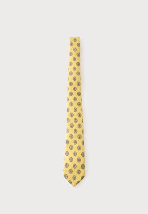 Cravate jaune avec un motif répétitif d'ovales bleus et blancs à motifs floraux sur un fond gris clair.