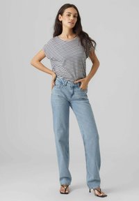 Gestreepte grijze en witte blouse met korte mouwen, gecombineerd met lichtblauwe high-waisted straight-leg jeans en zwarte sleehakken.