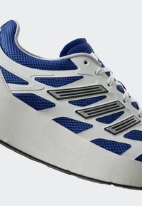 Blå mesh-sneakers med vit gummisula, silverdetaljer och grå detaljer. Har en strukturerad yta och distinkta ventilationshål.