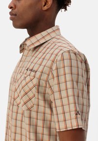 Korte mouwen geruite overhemd in beige met oranje en bruine lijnen, met een kraag, een knoopzak en een logo op de borst.