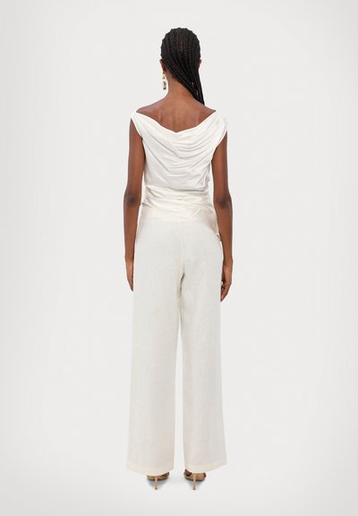 White draped top paired with high-waisted, beige wide-leg pants. The fabric has a smooth texture, featuring minimalistic design elements.