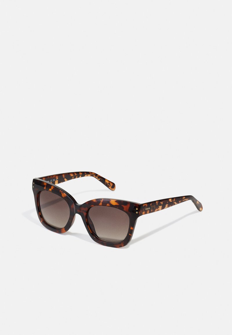 Occhiali da sole tartarugati con una montatura spessa, lenti sfumate e dettagli testurizzati sulle tempie. Il materiale sembra essere plastico.