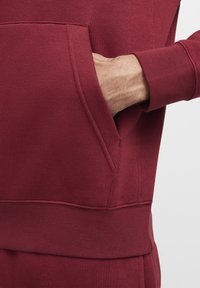 Bordeaux sweatshirt met een buidelzak. Voorzien van ribgebreide manchetten en zoom, een gladde textuur en een aansluitende pasvorm.