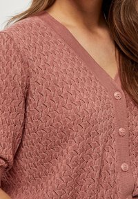 Ljusrosa stickad cardigan med V-ringning, strukturerat mönster, korta ärmar och fyra matchande knappar framtill.