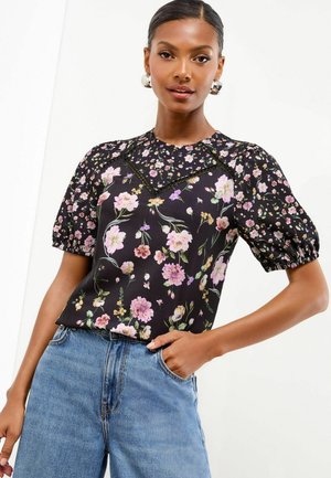 Schwarzes Blumenshirt mit Puffärmeln, das mit rosa und gelben Blumen verziert ist, einen runden Halsausschnitt hat und dekorative Stickereien entlang der Nähte aufweist.