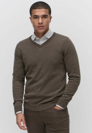 Brown knitted sweater with a v-neck design, featuring ribbed cuffs and hem. Worn over a white and gray striped collared shirt.