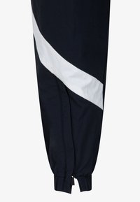 Námornícke tepláky s diagonálnym bielym pruhom, elastickým manžetou na členku a bočným švom. Vyrobené z hladkého, ľahkého materiálu.
