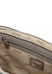 Portafoglio grigio con zip, caratterizzato da un esterno liscio e testurizzato, con un interno beige che presenta il logo "GUESS" ripetuto e una piccola tasca con zip.