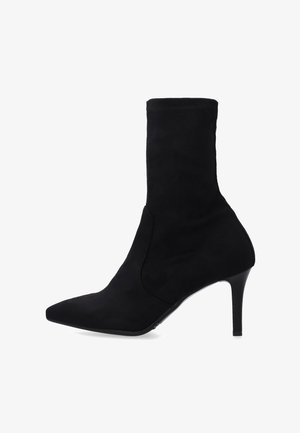 Czarne zamszowe botki za kostkę z długim noskiem, dopasowaną cholewką i eleganckim, wysokim obcasem. Gładka tekstura z minimalną ilością przeszyć.