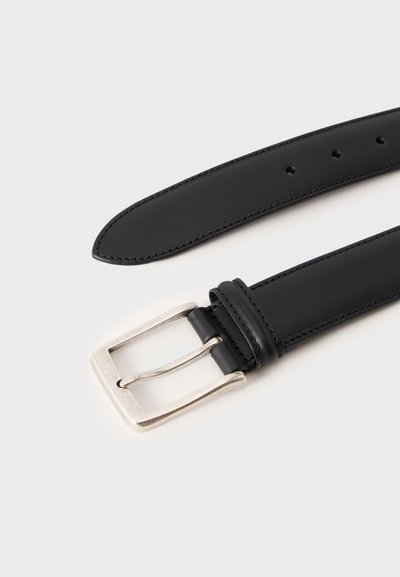 Ceinture en cuir noire avec une boucle rectangulaire en métal argenté et plusieurs trous d'ajustement sur un fond clair.