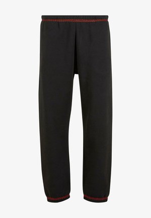 Črne trenirke z elastičnim pasom, rdečimi šivi na pasu in robovih, z gladko teksturo in sproščenim krojem.