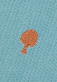Kleine oranje geborduurde boom op een textuurachtige lichtblauwe stof achtergrond.