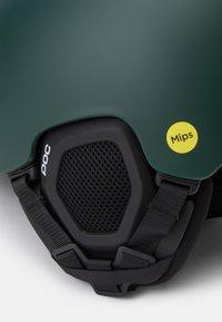 Vihreä hiihtokypärä, jossa on matta pinta, mustat verkkotuulettimet, POC-brändäys ja keltainen MIPS-tarra sivussa.