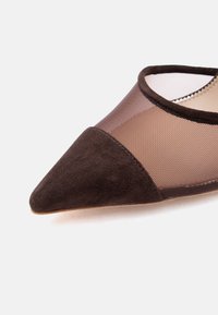 Πλατφόρμα με μυτερό δάχτυλο, με σκούρο καφέ σουέτ άκρο και διαφανές επάνω μέρος από δίχτυ, με λεπτή ραφή και εσωτερική μπεζ επένδυση.