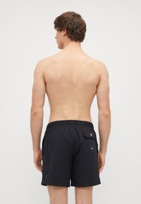 Czarne szorty do pływania o luźnym kroju, z elastycznym pasem i tylną kieszenią z zapięciem na zatrzask. Lekki, gładki materiał.