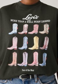 Μαύρο μπλουζάκι με γραφικό από 12 καουμπόικες μπότες σε διάφορα χρώματα και σχέδια. Το κείμενο από πάνω γράφει "Levi's® More Than A Well Worn Legend."