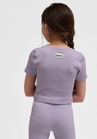 Lila ribbad tvådelad outfit med korta ärmar. Har en liten etikett på baksidan med "hummel"-logotyp. Slät textur och figursydd design.