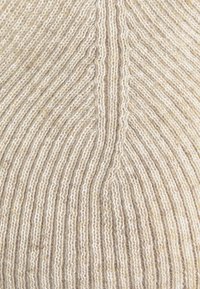 Beige gebreide muts met verticale ribbelstructuur, voorzien van een gladde, zachte afwerking en een ronde bovenkant. Gestikte lijnen creëren subtiele patronen.
