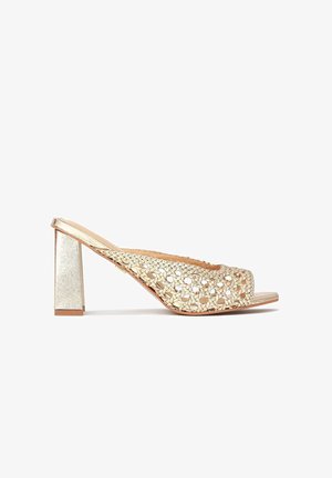 Guld slingback højhælede sandaler med vævet, åben tå-design og blokhæle på en hvid baggrund.