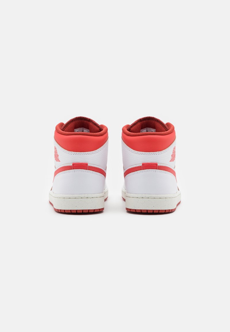 Zapatillas altas blancas con acentos rojos, material de cuero suave, tobillo acolchado y suela de goma texturizada. Cuenta con un logo en el talón.