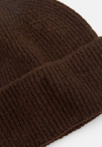 Berretto di maglia marrone con una texture a coste e un bordo piegato. Il tessuto sembra morbido e spesso, adatto per il clima più freddo.
