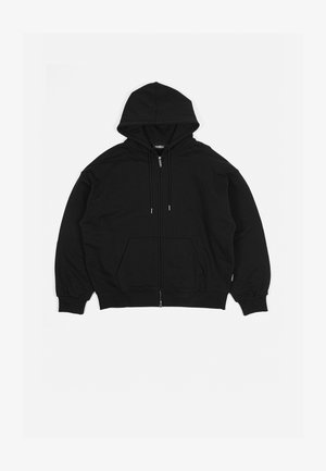 Crna dukserica s patentnim zatvaračem napravljena od mekanog materijala. Ima kapuljaču, vezice, dva prednja džepa i rebraste manžete i donji rub.