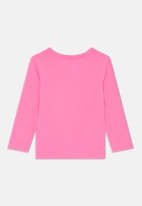 Chemise à manches longues en coton de couleur rose vif. Col rond avec une texture lisse et sans motifs ni attaches supplémentaires.